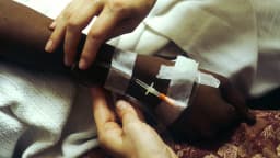 Mãos de paciente recebendo quimioterapia por via intravenosa