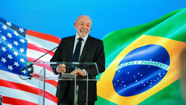 O presidente Lula discursa em pé de um púlpito com bandeiras do Brasil e dos Estados Unidos ao fundo, durante entrevista coletiva em Washington