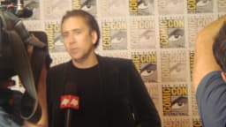 Nicolas Cage em evento de Comic-Con, diante de microfones