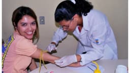 Mulher faz exame de sangue com profissional de saúde em consultório