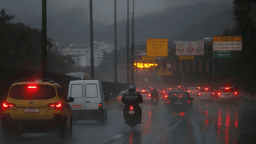 Carros e motociclista trafegam sob chuva forte em via expressa no Rio de Janeiro