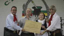 Grupo de pessoas em trajes tradicionais gaúchos participa de cerimônia em evento de CTG