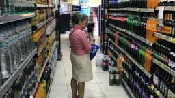 Mulher observa rótulos de produtos nas prateleiras de um supermercado