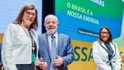 A presidente da Petrobras, Magda Chambriard, ao lado do presidente Lula, sorrindo em evento oficial