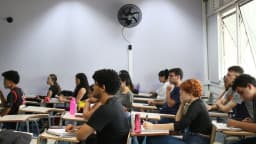 Candidatos sentados em sala de aula durante prova de concurso público