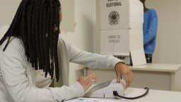 Eleitora vota em urna eletrônica dentro de cabina de votação da Justiça Eleitoral