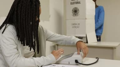 Eleitora vota em urna eletrônica dentro de cabina de votação da Justiça Eleitoral