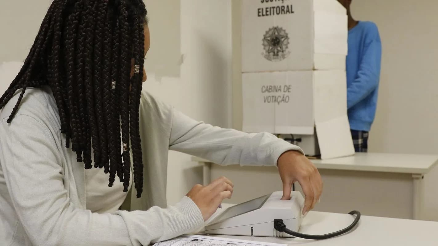 Eleitora vota em urna eletrônica dentro de cabina de votação da Justiça Eleitoral