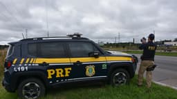 Viatura da Polícia Rodoviária Federal e agente em fiscalização no acostamento de uma rodovia do Paraná (foto de arquivo)