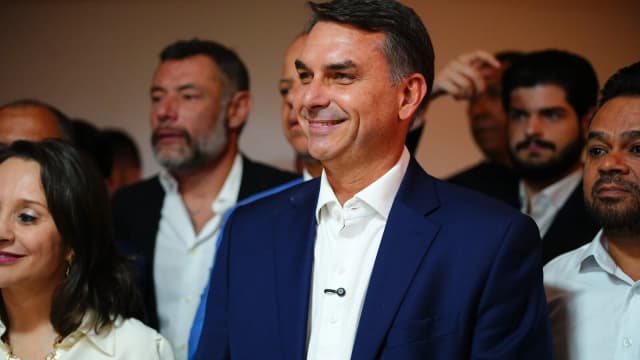 Flávio Bolsonaro sorri cercado de apoiadores em evento de campanha