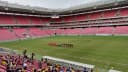 Times perfilados em campo antes de partida na Arena de Pernambuco, estádio do Santa Cruz, com arquibancadas vermelhas ao fundo