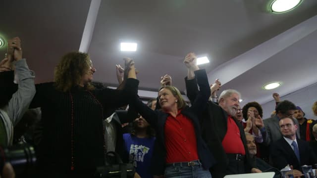 Presidente Lula em coletiva de imprensa, gesticulando ao lado de apoiadores