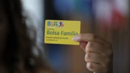 Mulher segura cartão do programa Bolsa Família