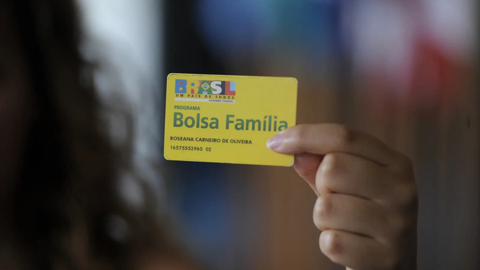 Mulher segura cartão do programa Bolsa Família
