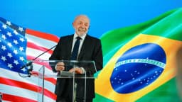 O presidente Lula sorri em coletiva de imprensa em Washington, com bandeiras dos Estados Unidos e do Brasil ao fundo
