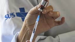 Profissional de saúde prepara uma dose de vacina; foto de arquivo sobre vacinação, sem mostrar a MenQuadfi.