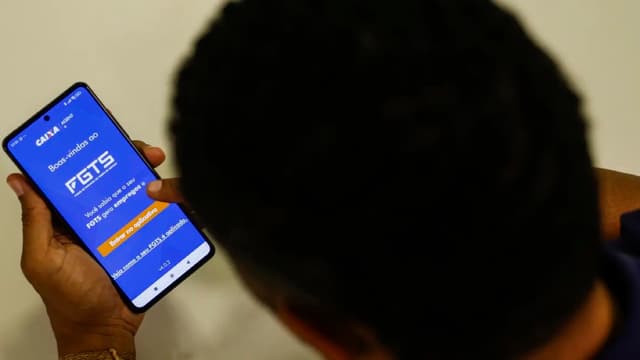 Pessoa segura um celular com a tela de boas-vindas do aplicativo do FGTS aberta