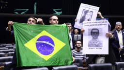 Jair Bolsonaro e Eduardo Bolsonaro seguram bandeira do Brasil no plenário da Câmara dos Deputados