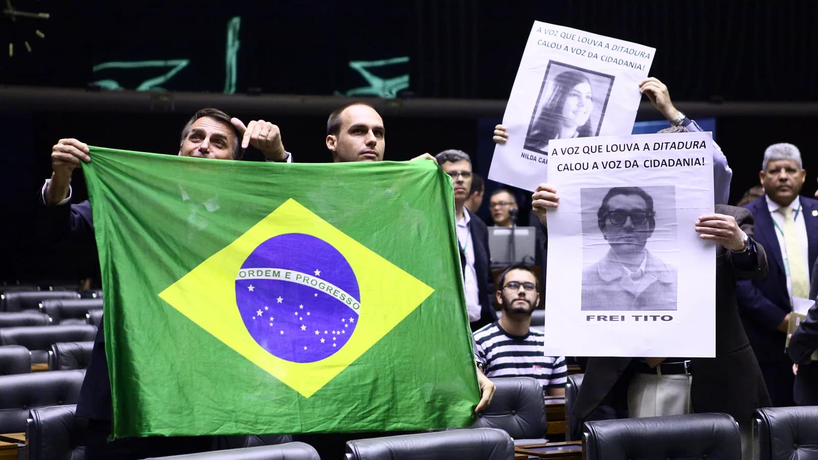 Jair Bolsonaro e Eduardo Bolsonaro seguram bandeira do Brasil no plenário da Câmara dos Deputados
