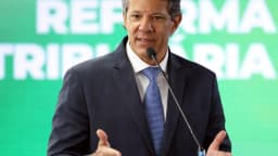 O ministro da Fazenda, Fernando Haddad, discursa com painel da Reforma Tributária ao fundo