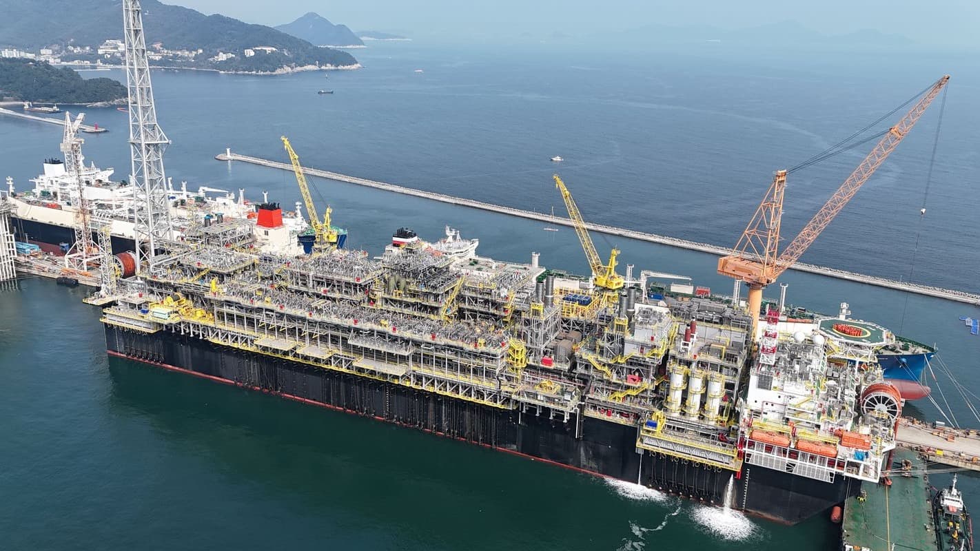 Vista aérea de plataforma FPSO de petróleo do pré-sal atracada em estaleiro, com guindastes ao redor