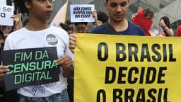 Manifestantes seguram cartazes contra censura digital em protesto em frente ao TSE em Brasília