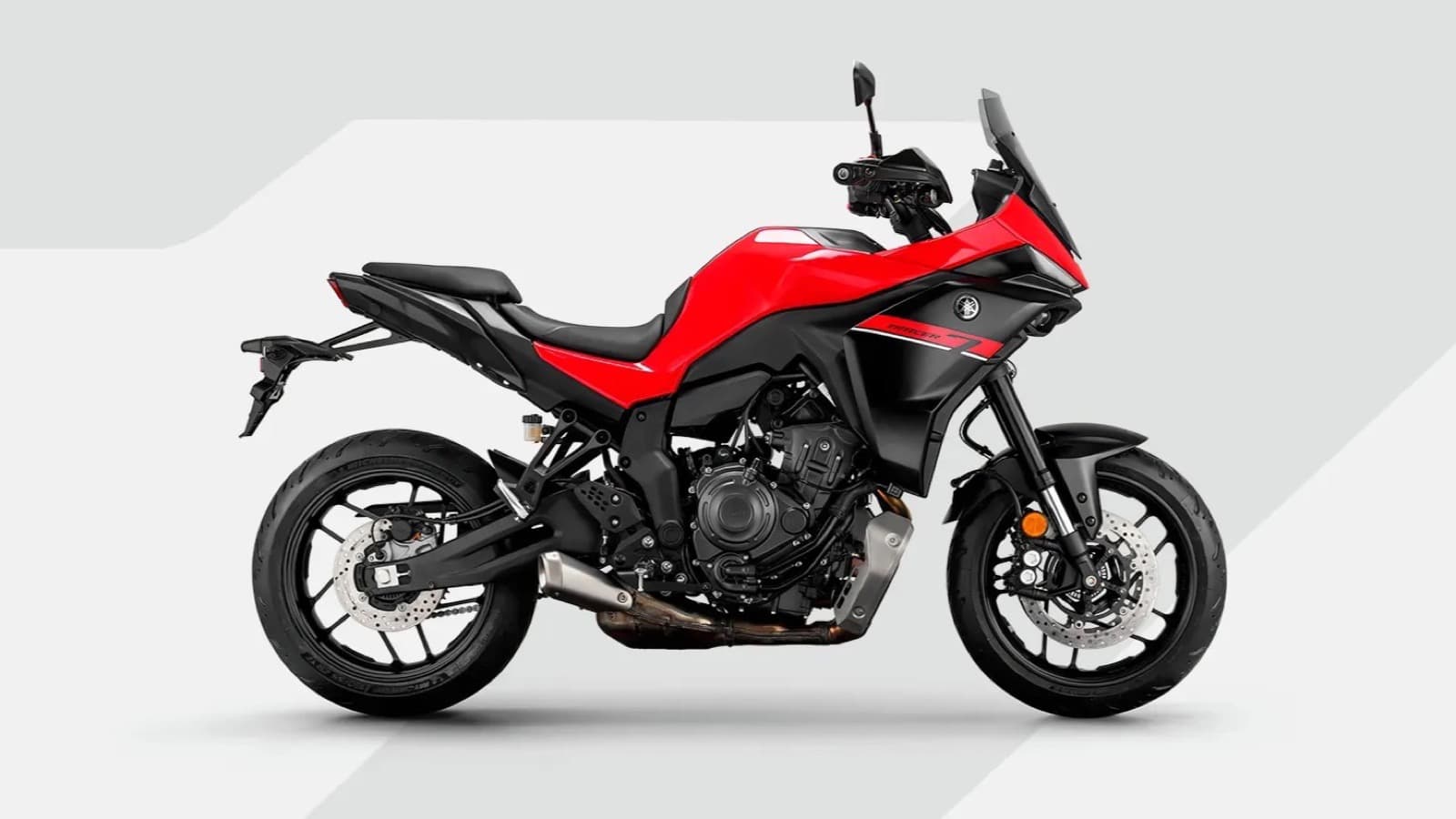 Moto Yamaha Tracer 7 na cor vermelha, vista de perfil, em foto de estúdio com fundo cinza claro