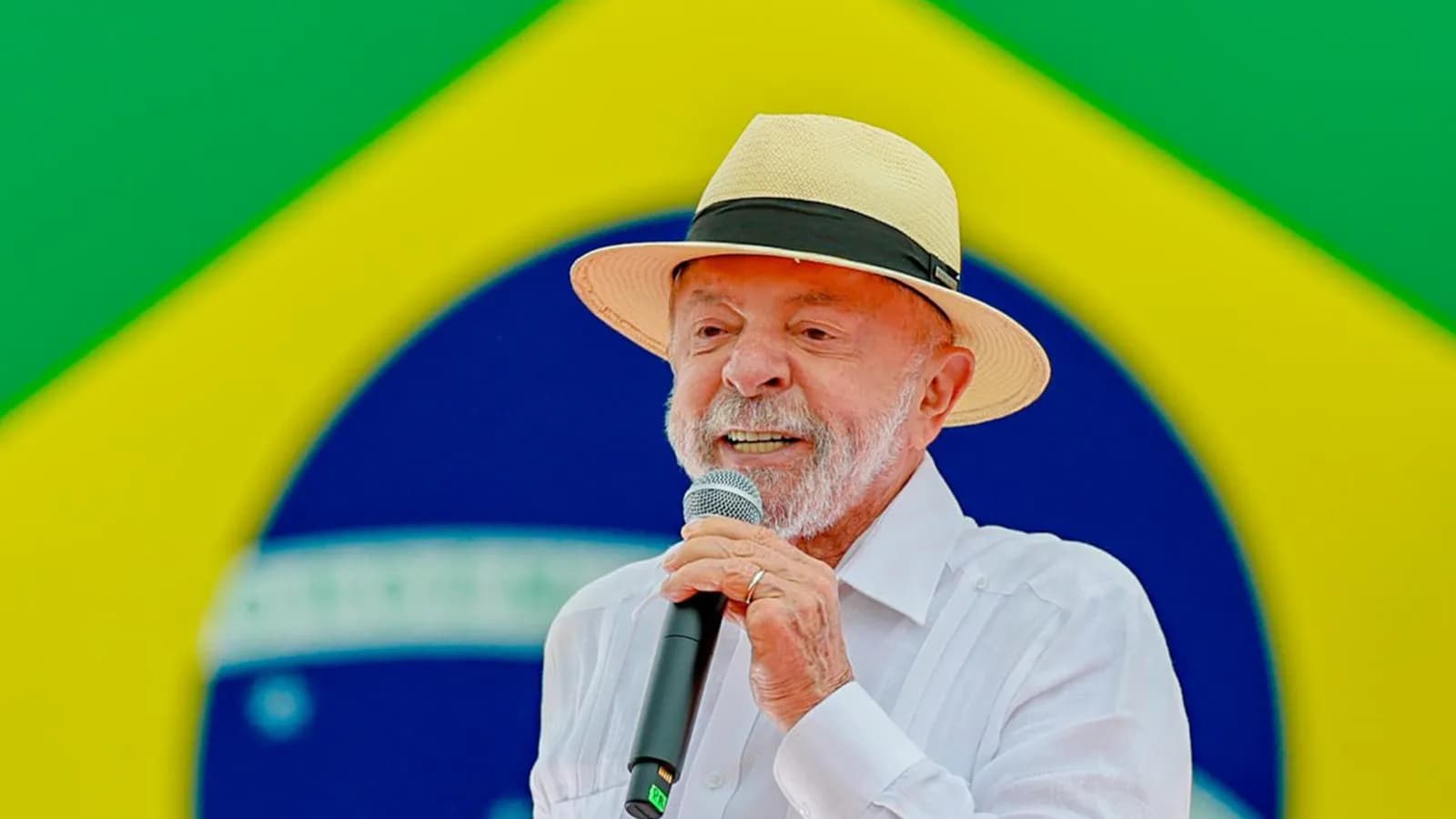 Lula discursa ao microfone em ato de campanha no Rio de Janeiro, com uma bandeira do Brasil ao fundo