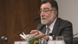 Patrus Ananias fala ao microfone segurando um exemplar da Constituição