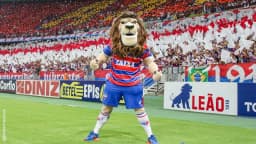 Mascote do Fortaleza, o leão Juba, em campo com a torcida tricolor ao fundo em jogo no Castelão