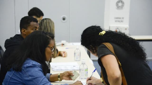 Eleitores conferem documento na mesa de votação antes de confirmar a identidade e votar