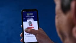 Homem segura celular com o aplicativo e-Título aberto, mostrando aviso de biometria não coletada