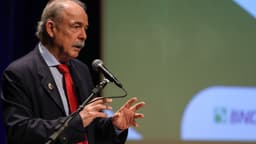 Aloizio Mercadante, presidente do BNDES, discursa em coletiva de imprensa em São Paulo, com o logotipo do banco ao fundo