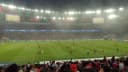 Torcedores do Flamengo acompanham jogo no Maracanã lotado, com o time em campo ao fundo