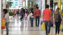 Consumidores caminham em galeria comercial com sacolas de compras (foto de arquivo, sem relação direta com as empresas citadas)