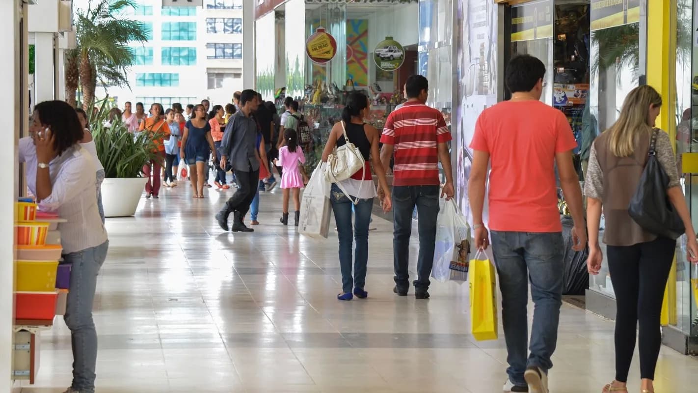 Consumidores caminham em galeria comercial com sacolas de compras (foto de arquivo, sem relação direta com as empresas citadas)