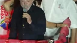 Lula fala ao microfone em ato de campanha à noite em Belo Horizonte, cercado por apoiadores