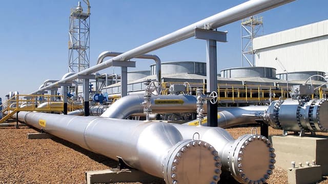 Estação de gasoduto com tubulações de aço e válvulas industriais sob céu azul, em imagem de arquivo