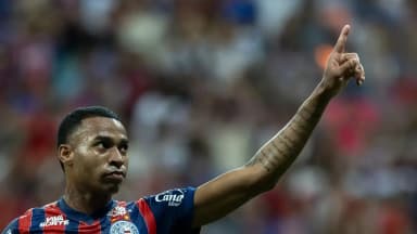 Jean Lucas, do Bahia, comemora gol apontando para o alto, com a torcida ao fundo