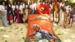 Mulheres do movimento quilombola seguram bandeira em homenagem a Mãe Bernadete