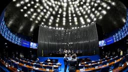 Plenário do Senado Federal durante sessão, com senadores em pé conversando e mesa diretora ao fundo