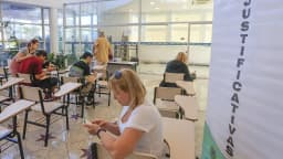 Eleitores preenchem formulário de justificativa eleitoral em posto da Justiça Eleitoral
