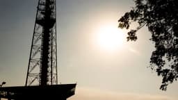 Torre de TV de Brasília em contraluz, com sol forte e céu esbranquiçado de tempo seco, em imagem de arquivo