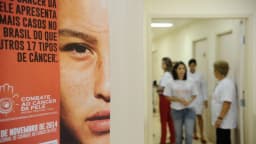 Cartaz de campanha de combate ao câncer de pele e profissionais de saúde em corredor de hospital (foto de arquivo, ilustrativa)