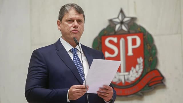O governador de São Paulo, Tarcísio de Freitas, discursa com papel nas mãos diante do brasão do estado