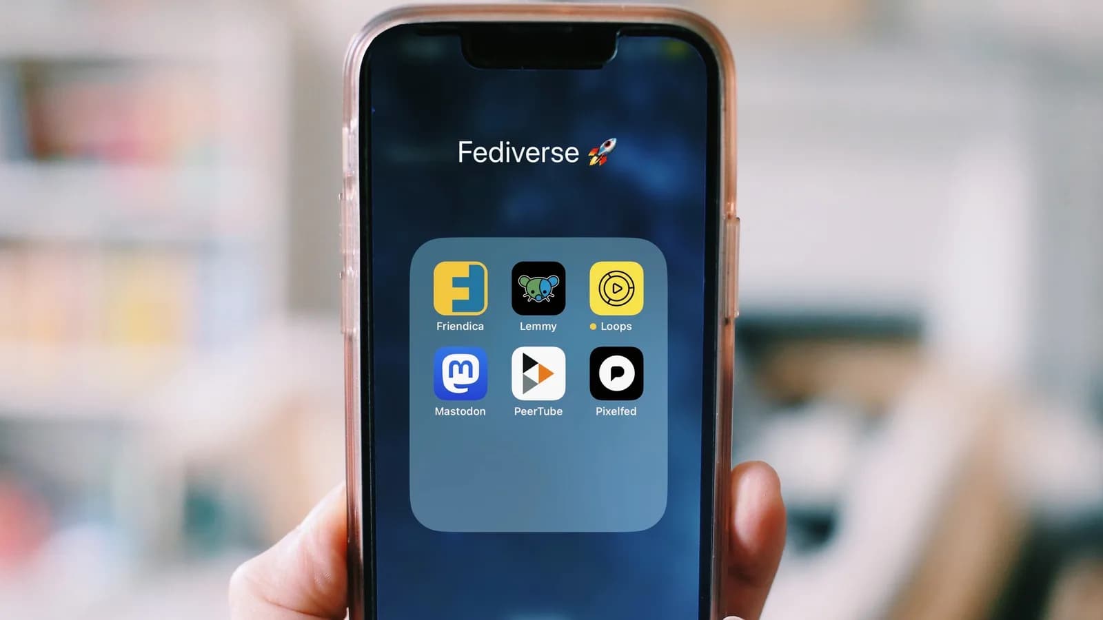 Mão segurando smartphone com ícones de aplicativos na tela