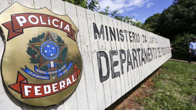 Placa da Polícia Federal e do Departamento de Polícia Federal em muro de concreto