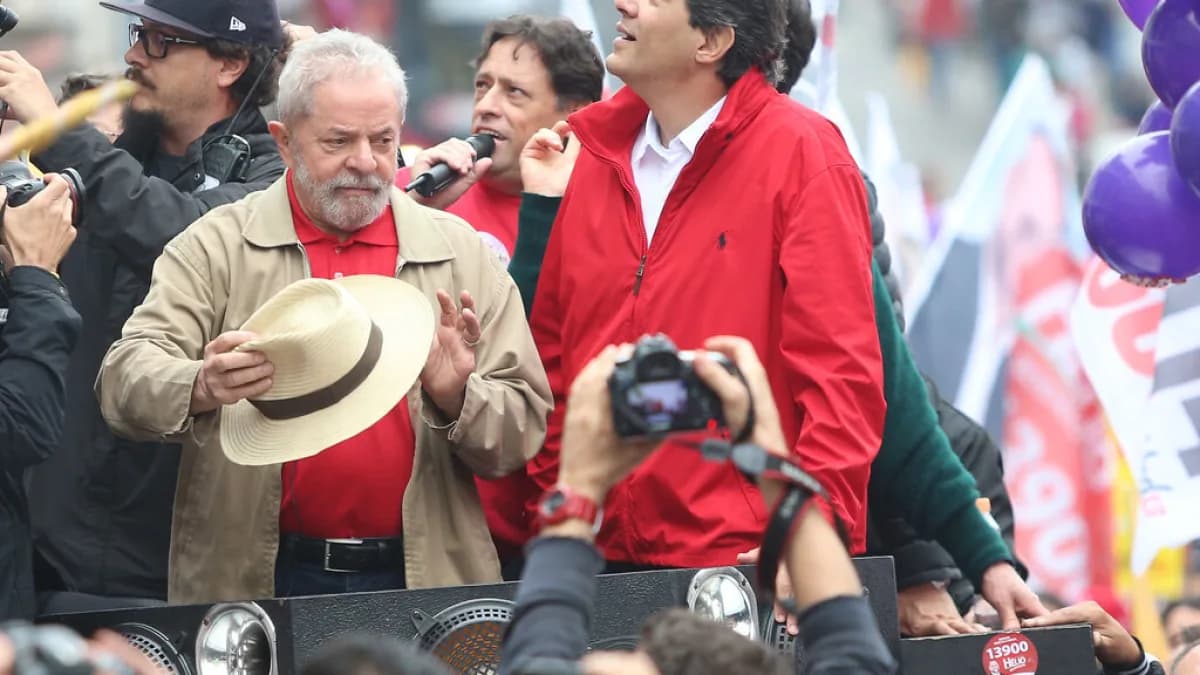 Lula e Fernando Haddad com os braços erguidos em ato de campanha do PT, cercados por apoiadores