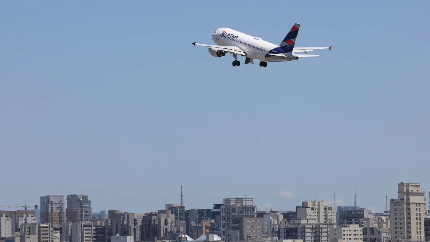 Avião decolando sobre o horizonte de uma cidade