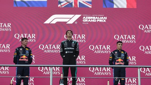 Max Verstappen no pódio ao lado de George Russell e outro piloto em corrida da F1 2026 (foto de arquivo do GP do Azerbaijão)